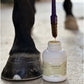 photo des pieds d'un cheval  a coté d'un pot d'huile de cade Nutragile avec un pinceau qui s'égoutte 